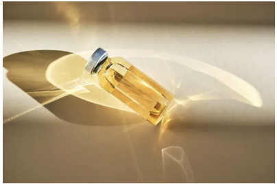 A small glass vial of golden peptide solution, illuminated by warm light